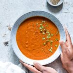Tomato Soup Topped With Herbs On Light Blue Background