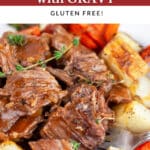 Instant Pot pot roast with gravy and roasted potatoes and carrots in white bowl with fork.