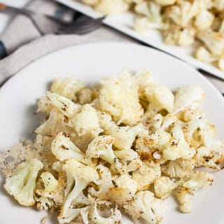Roasted cauliflower with Parmesan cheese on white plate.