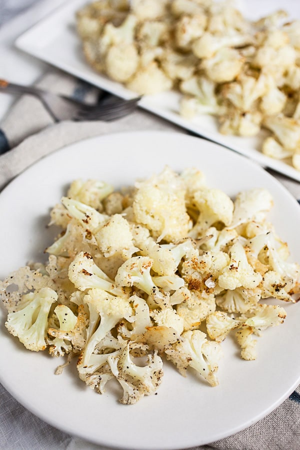 Roasted cauliflower with Parmesan cheese on white plate.