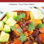 Slow cooker veggie chili with diced avocado, lime wedge, and cilantro in white bowl.