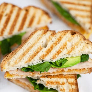 Chipotle chicken panini cut in half and stacked on white surface.