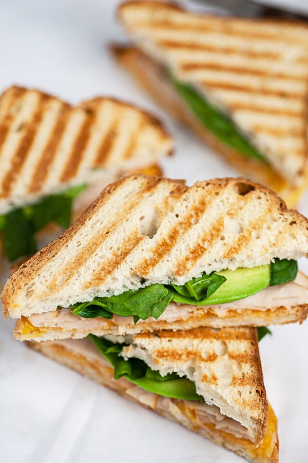 Chipotle chicken panini cut in half and stacked on white surface.