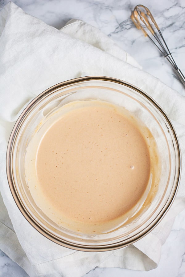 Chipotle mayo in small glass bowl next to whisk.