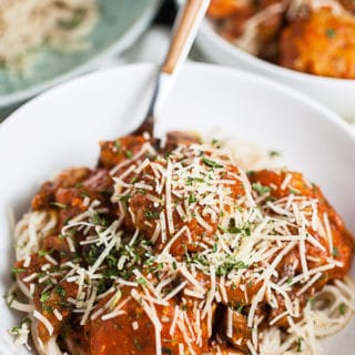 Spaghetti and turkey meatballs in marinara sauce with Parmesan cheese in white bowls.