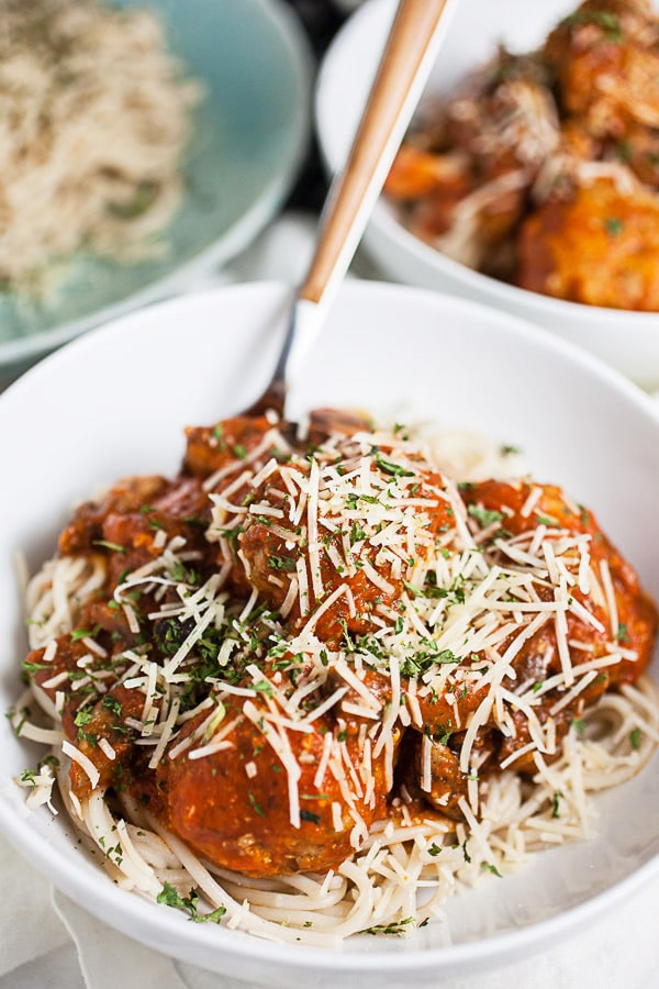 Spaghetti and turkey meatballs in marinara sauce with Parmesan cheese in white bowls.