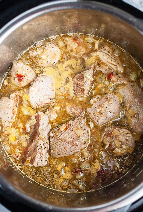 Chunks of pork shoulder, spices, and juices cooking in Instant Pot.