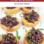 Kalamata olive tapenade on white platter garnished with minced chives.