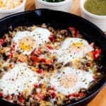 Southwest breakfast skillet with eggs on table next to bowls of toppings.