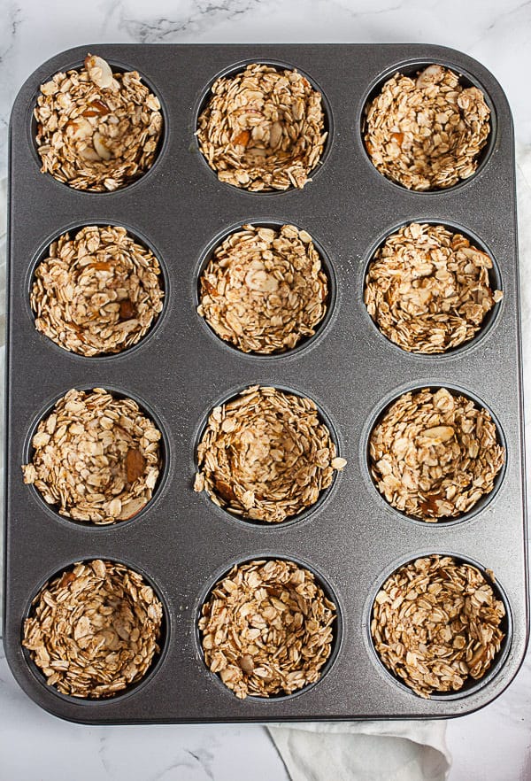 #ad These Greek Yogurt Oatmeal Cups are the perfect easy and healthy breakfast recipe! The oats are mixed with coconut oil, lemon zest, and cinnamon and then baked until crispy. They're filled with yogurt that's creamy and lightly sweetened with honey. Great for a brunch, dessert, or to serve at a party! @GreekGodsYogurt #oatmeal #yogurt #cups #healthy #glutenfree Oats pressed into a muffin tin.