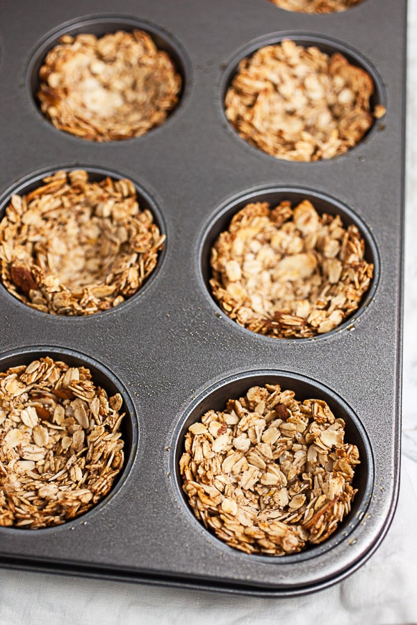 #ad These Greek Yogurt Oatmeal Cups are the perfect easy and healthy breakfast recipe! The oats are mixed with coconut oil, lemon zest, and cinnamon and then baked until crispy. They're filled with yogurt that's creamy and lightly sweetened with honey. Great for a brunch, dessert, or to serve at a party! @GreekGodsYogurt #oatmeal #yogurt #cups #healthy #glutenfree Baked oatmeal cups in muffin tin.