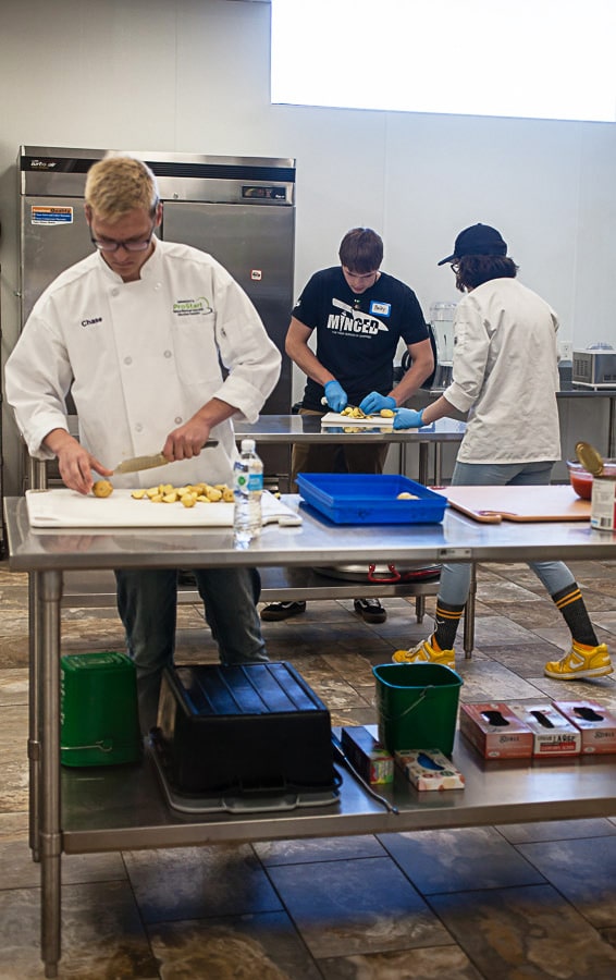 Student chefs prepare food in kitchen.