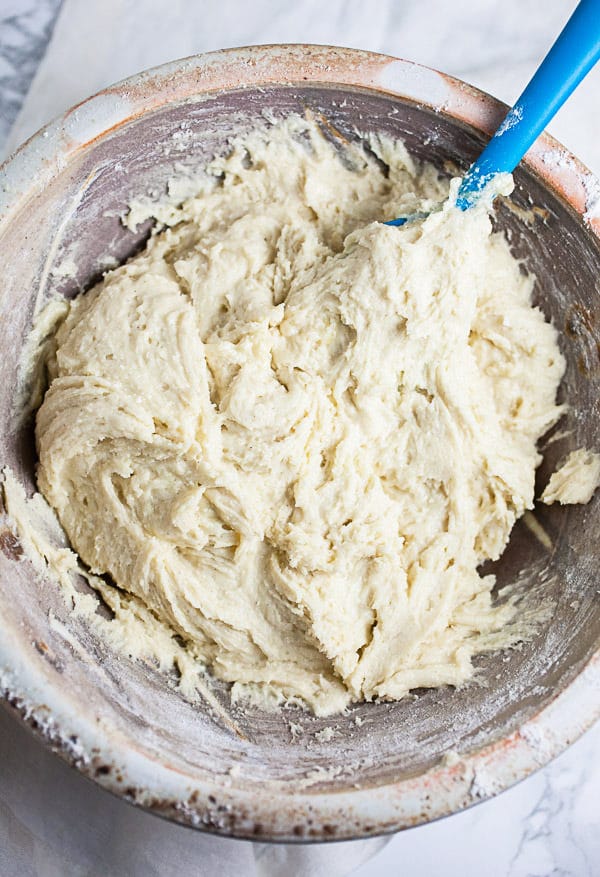 Rhubarb bread batter in ceramic bowl with blue spatula.