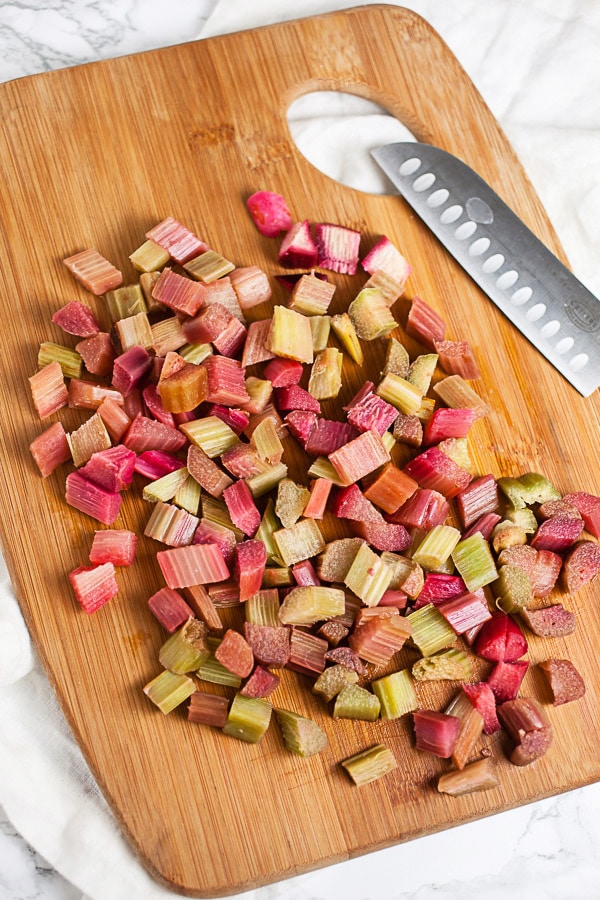 Diced rhubarb on wooden cutting board with knife.