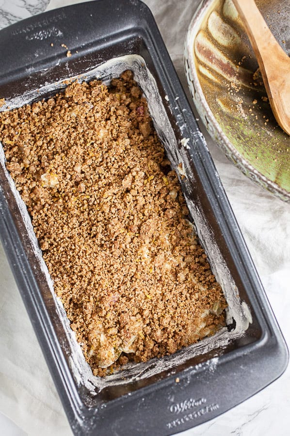 This Old Fashioned Rhubarb Bread is easy to make and totally delicious! It's made with sour cream so it's super moist. A layer of cinnamon streusel is baked into the middle of the bread giving it great crunch and texture. Perfect for breakfast, brunch, or dessert! This recipe is gluten free as well. A great way to welcome the spring and summer season! #rhubarb #bread #breakfast #streusel #glutenfree Half of rhubarb bread batter with layer of streusel in metal bread pan.
