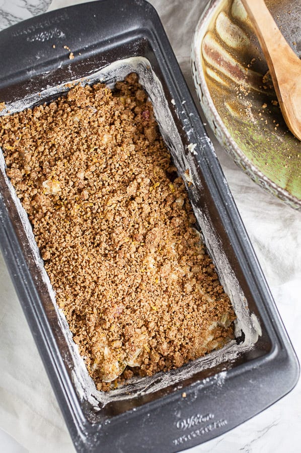 Half of rhubarb bread batter with layer of streusel in metal bread pan.