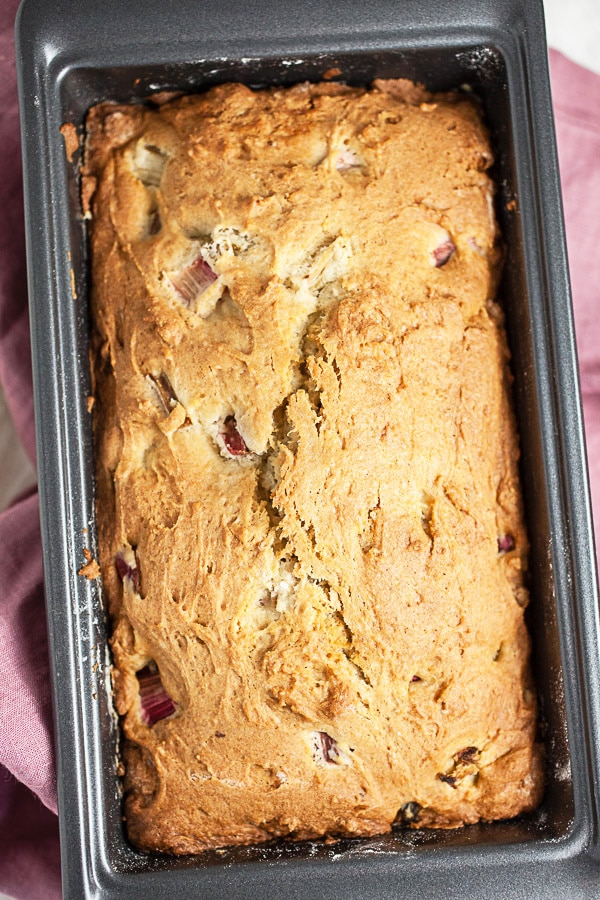 This Old Fashioned Rhubarb Bread is easy to make and totally delicious! It's made with sour cream so it's super moist. A layer of cinnamon streusel is baked into the middle of the bread giving it great crunch and texture. Perfect for breakfast, brunch, or dessert! This recipe is gluten free as well. A great way to welcome the spring and summer season! #rhubarb #bread #breakfast #streusel #glutenfree Baked rhubarb bread in metal loaf pan.