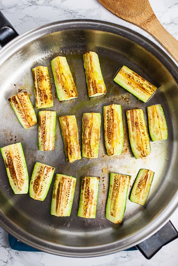 This Skillet Zucchini Parmesan recipe makes the perfect easy and healthy weeknight dinner for one! The pasta is cooked in a rich tomato sauce, combined with fresh zucchini, and then baked in the oven. It's topped with mozzarella and Parmesan cheese. This meal is vegetarian and gluten free! #pasta #zucchini #skillet #vegetarian #glutenfree Zucchini wedges sautéed in skillet.