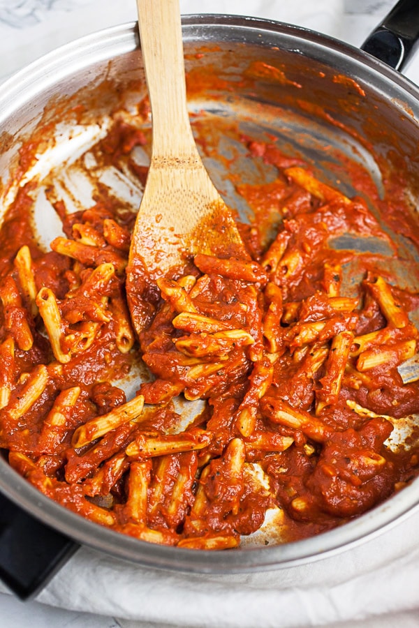 Penne noodles cooked in marinara sauce in skillet.