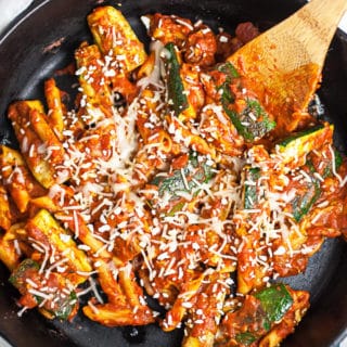 Zucchini Parmesan in cast iron skillet with wooden spoon.