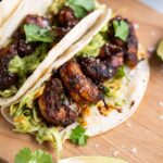 Blackened shrimp tacos with guacamole and fresh cilantro on corn tortillas.