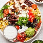 Southwest Santa Fe salad in white bowl with small container of dressing.