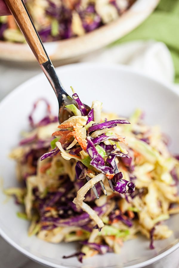 Forkful of miso ginger cabbage slaw lifted from white bowl.