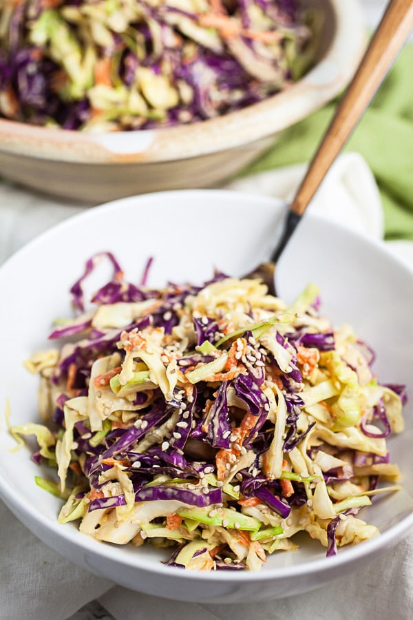 Red and green cabbage slaw in white bowl with fork.