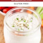 Chunky blue cheese dressing in glass jar on wooden board with raw veggies.