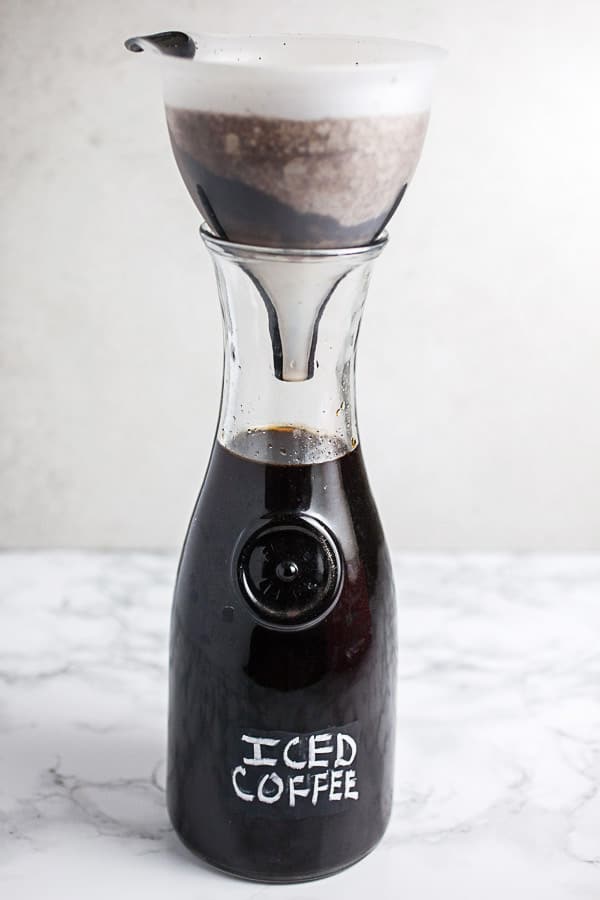 Coffee strained into a glass carafe through a funnel.