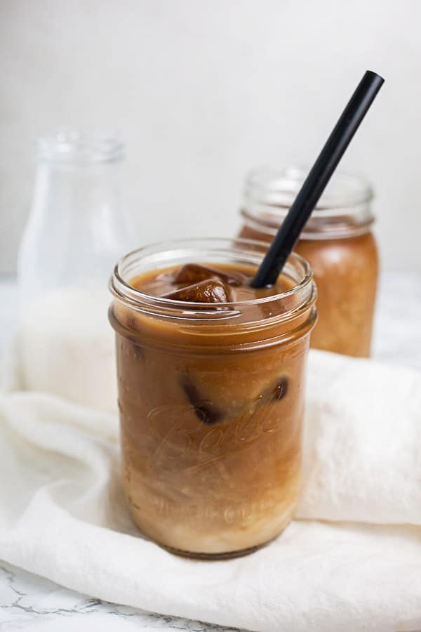 Cold brew coffee with almond milk in glass mason jar with straw.