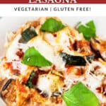 Garden vegetable lasagna on white plate garnish with fresh basil.