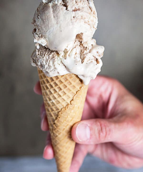Hand holding peanut butter cup ice cream cone.