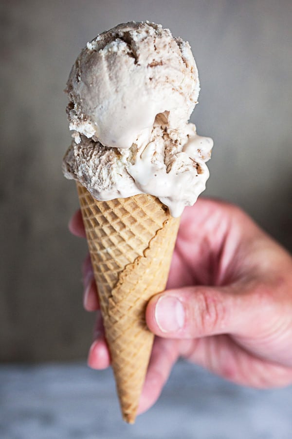 Hand holding peanut butter cup ice cream cone.