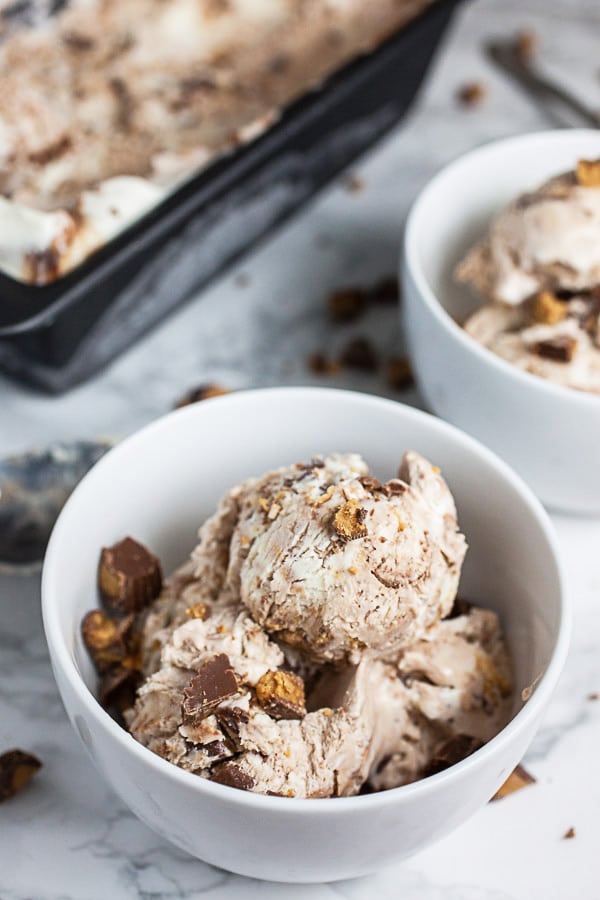 Peanut butter cup ice cream in small white bowls in front of bread pan.