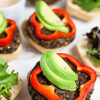 Open faced black bean mushroom burgers with red bell pepper rounds and sliced avocado.