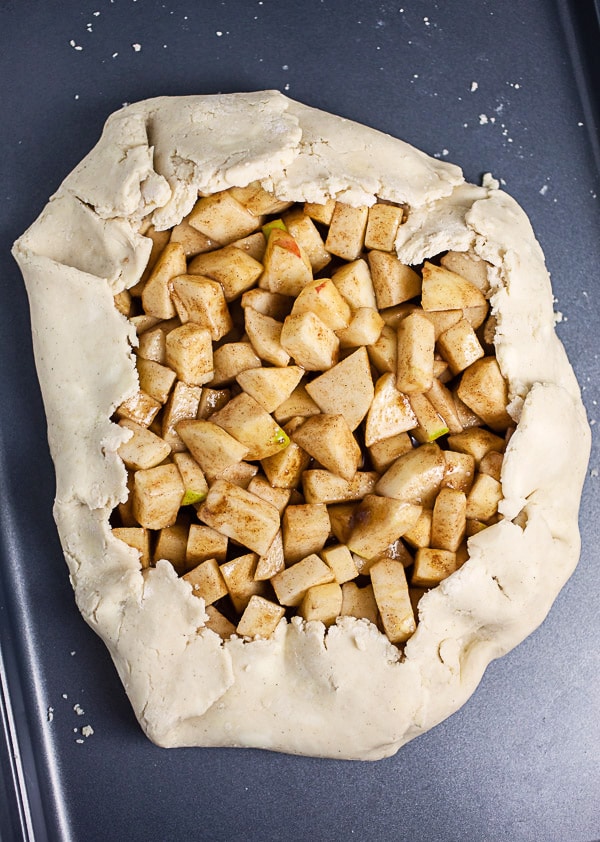 Unbaked apple galette on metal baking sheet.