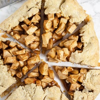 Galette cut into pieces on white surface next to knife.