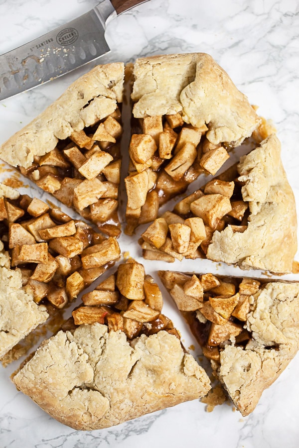 Galette cut into pieces on white surface next to knife.