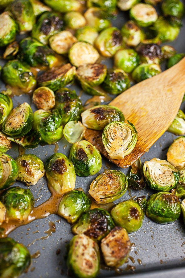 Roasted Brussels sprouts topped with maple mustard glaze on metal baking sheet.