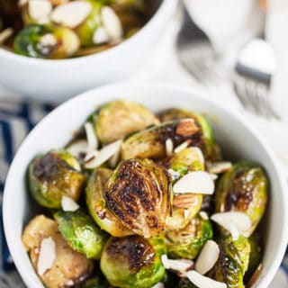 Roasted Brussels sprouts with sliced almonds in small white bowls.