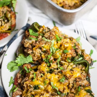 Stuffed poblano peppers with ground turkey, rice, and cheese on small white plates.