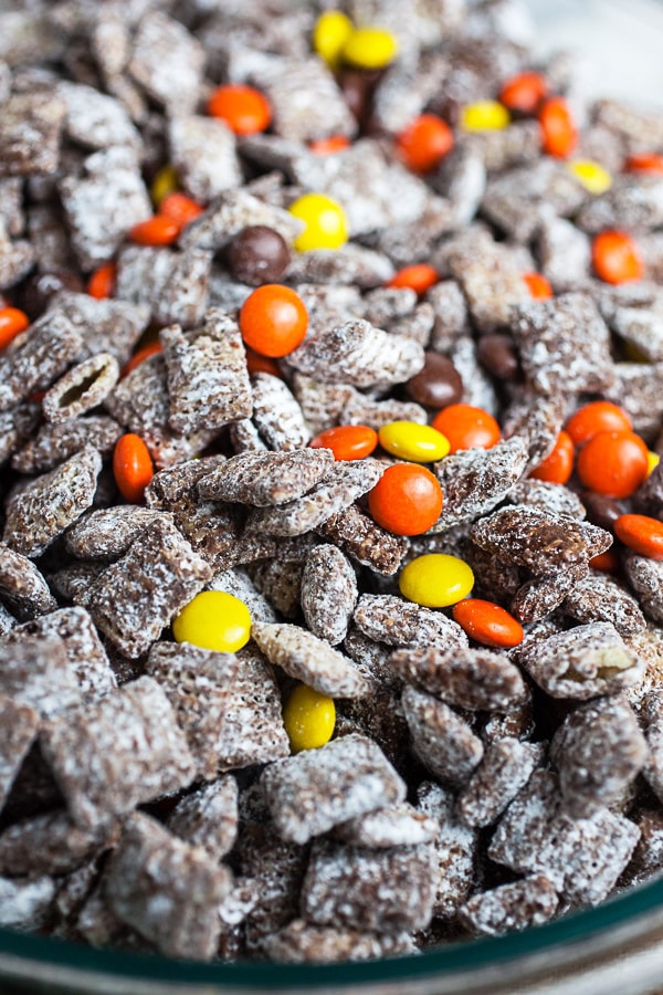 Halloween puppy chow with Reese's Pieces candies in large glass mixing bowl.
