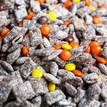 Halloween puppy chow with Reese's Pieces candies in large glass bowl.