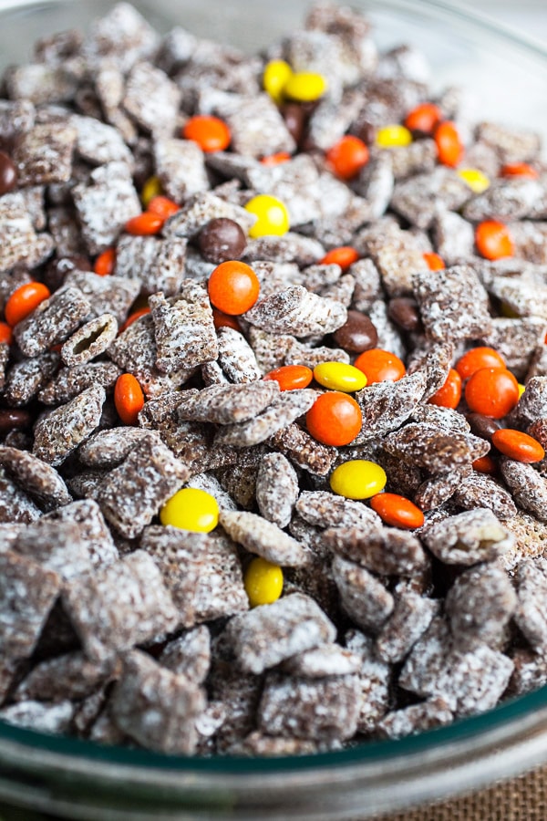 Halloween puppy chow with Reese's Pieces candies in large glass bowl.