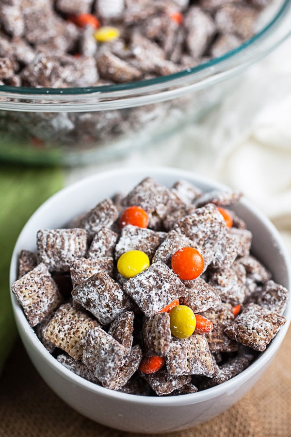 Puppy chow in small white bowl in front of large glass bowl.