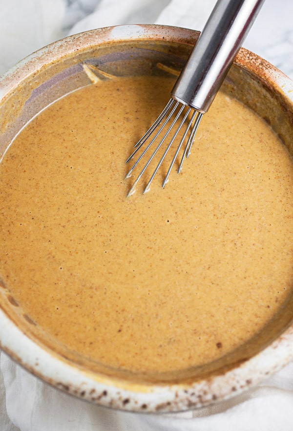 Pumpkin custard in ceramic bowl with metal whisk.