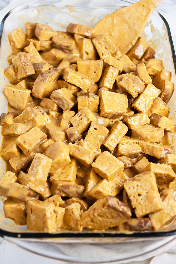 Bread cubes soaked in pumpkin custard mixture in glass baking dish.