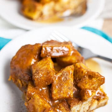 Pumpkin bread pudding with caramel sauce on small white plates.