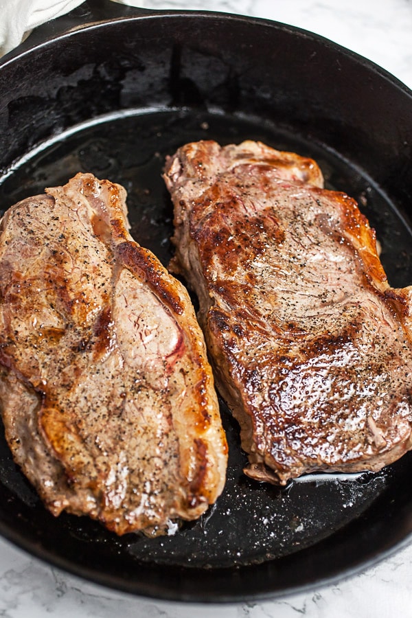 New York strip steaks seared in cast iron skillet.